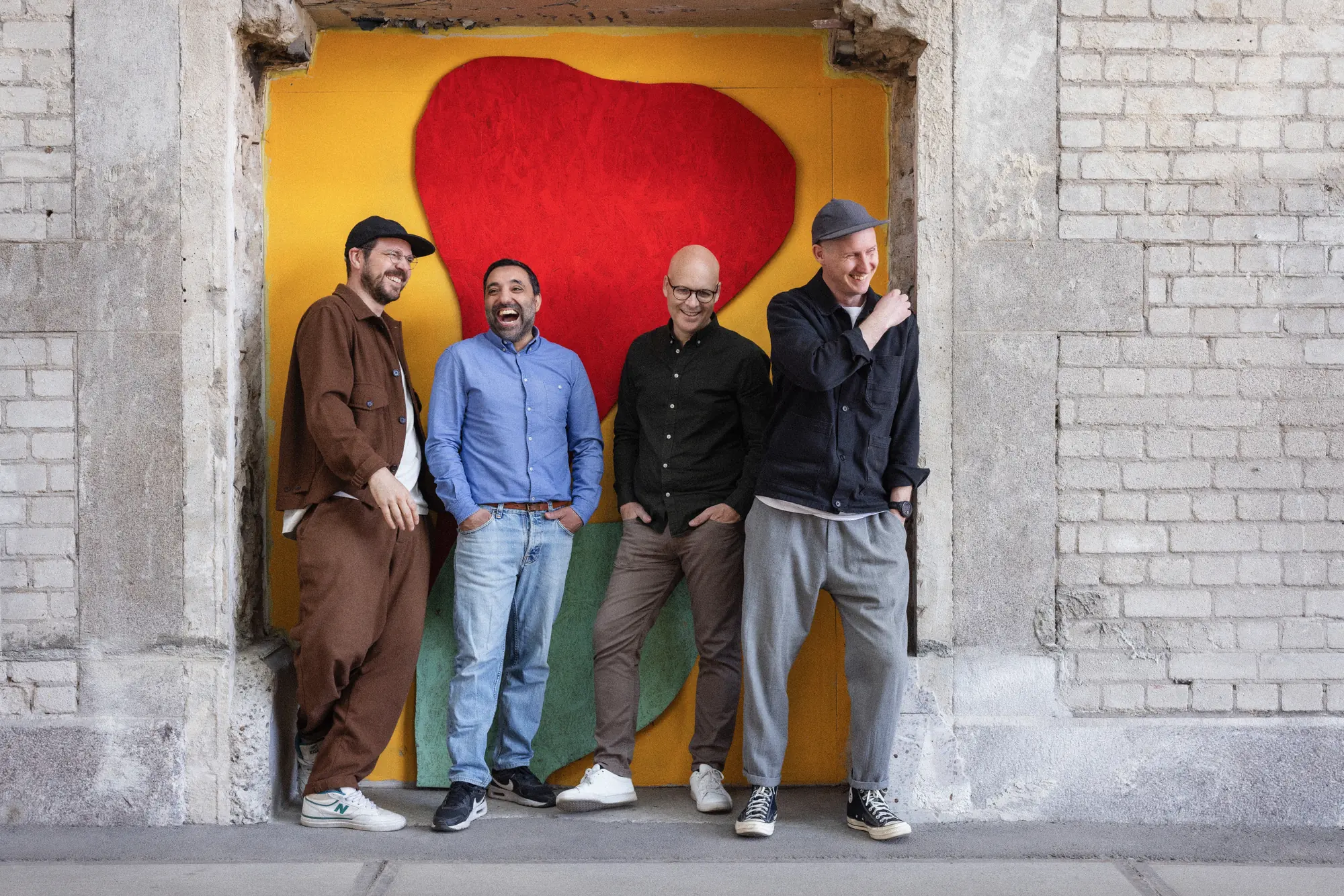 Nimio's four co-founders standing in front of a colourful painted wall
